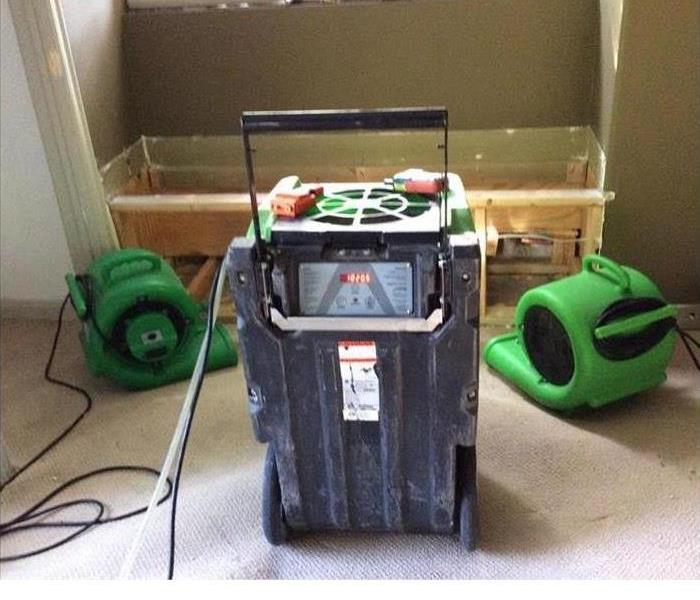 A previously water damaged room that has a SERVPRO green dehumidifier in it.