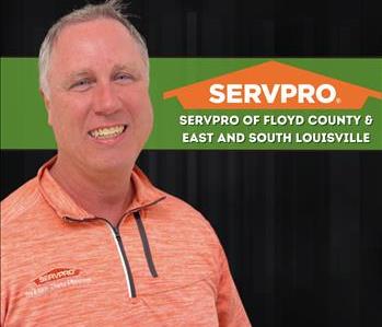 man smiling at camera with a black background and a SERVPRO logo