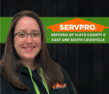 Woman wearing SERVPRO shirt standing in front of black wall with long brown hair
