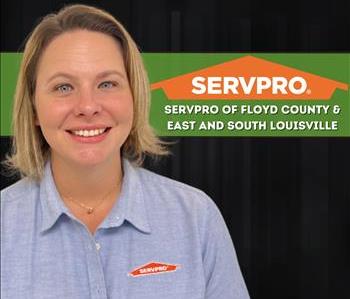 Woman with blonde hair wearing a SERVPRO shirt standing against a black wall