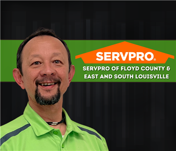man smiling at the camera with red hair and a servpro logo on the wall
